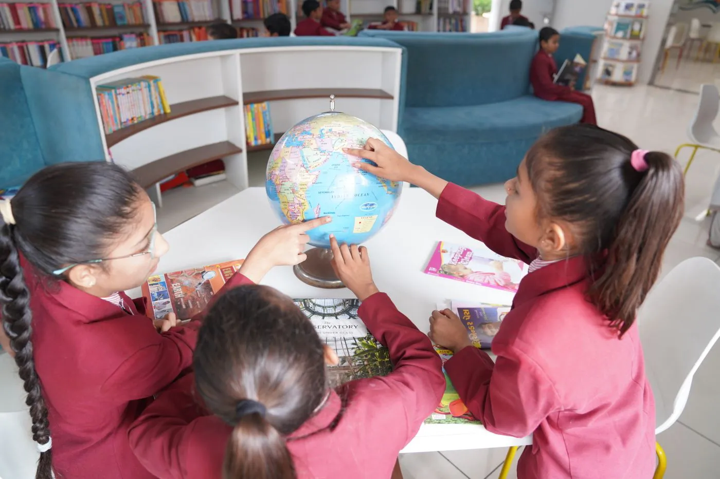 Three girls studying a globe together in the library