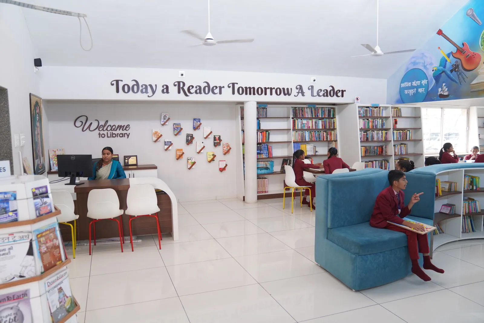 The Magnus library: white shelves, a blue reading sofa and a wall that reads Today a Reader, Tomorrow a Leader