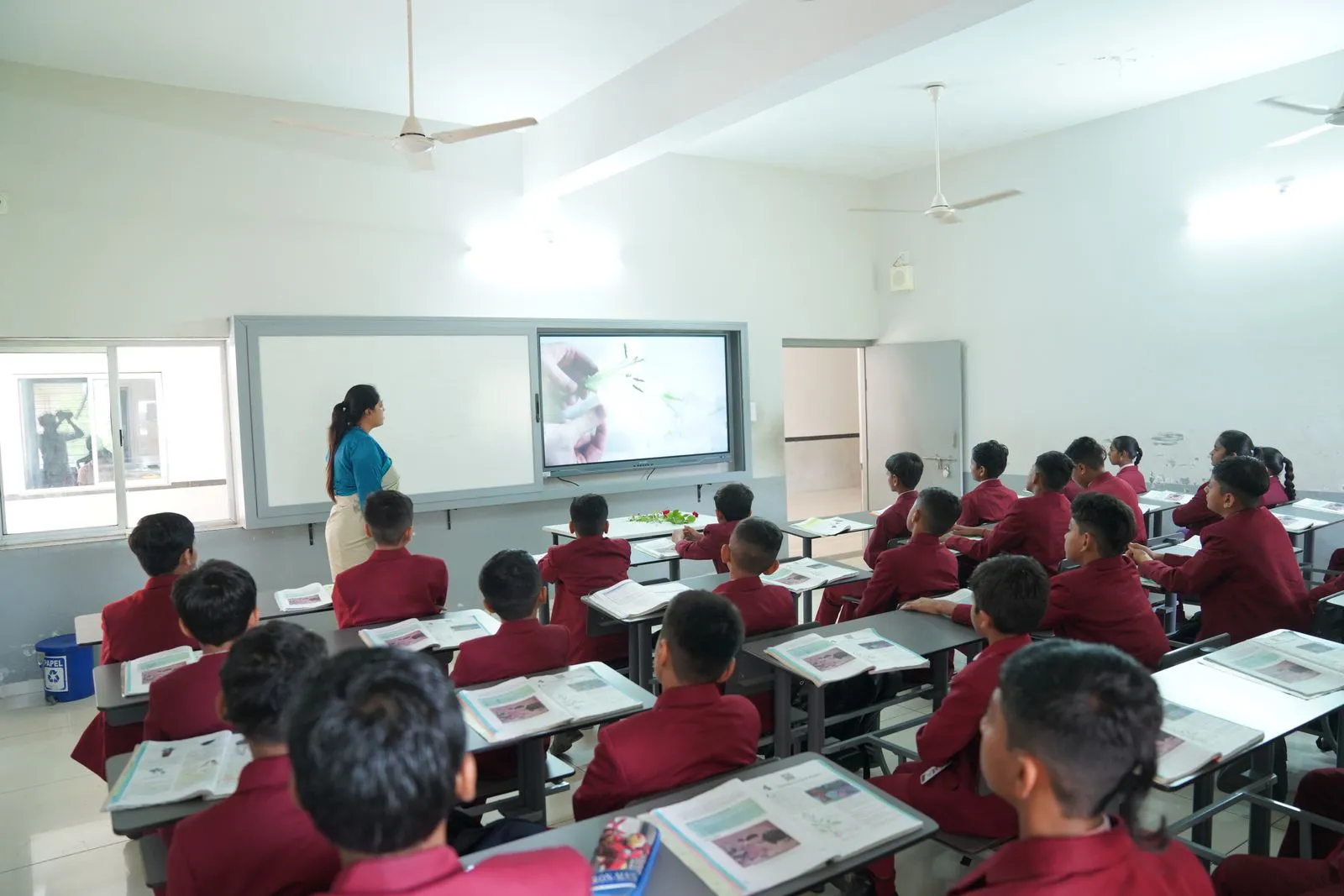 A bright classroom with students at desks watching a lesson on an interactive board