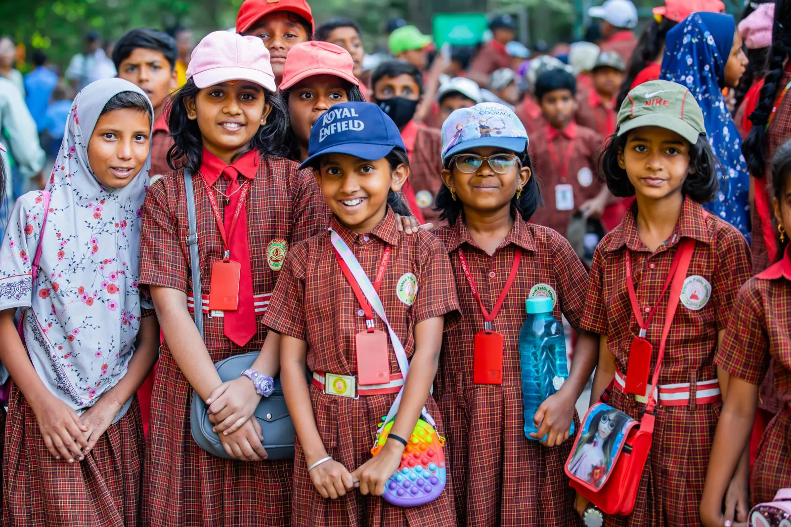 A large group of primary students in caps and uniform on an educational trip