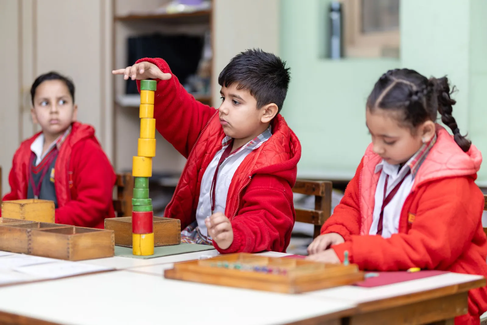 Three pre-primary children building a tower of coloured blocks